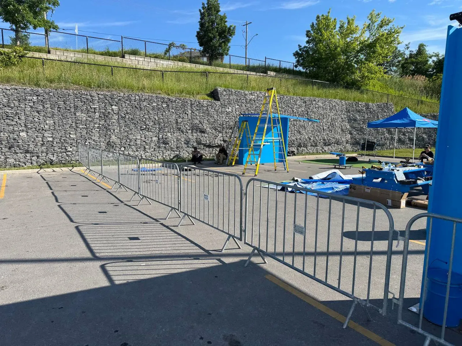 A line of galvanized steel crowd control barriers across an outdoor event build