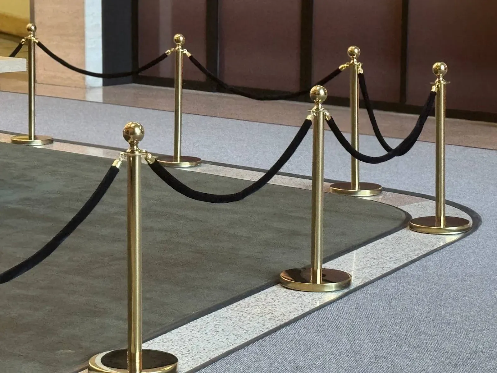 Close-up of gold rope stanchion posts carrying black velvet ropes